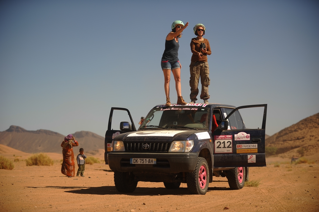 Mujeres compitiendo en el desierto paradas sobre su 4x4